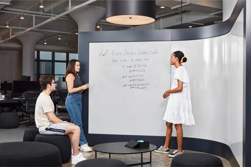People in a meeting room, one person is explaining something on a whiteboard.