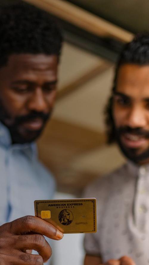 두 사람이 노트북과 American Express 카드를 들고 있는 모습