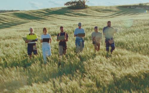 Video of tradies in a field walking and lifting laptops in the air