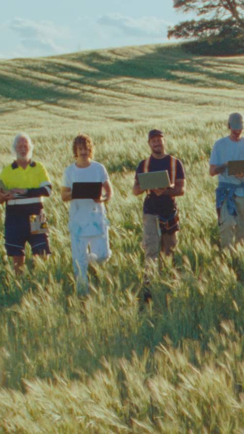 Video of tradies in a field walking and lifting laptops in the air