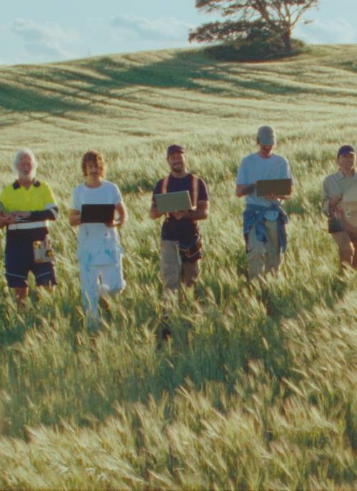 Video of tradies in a field walking and lifting laptops in the air