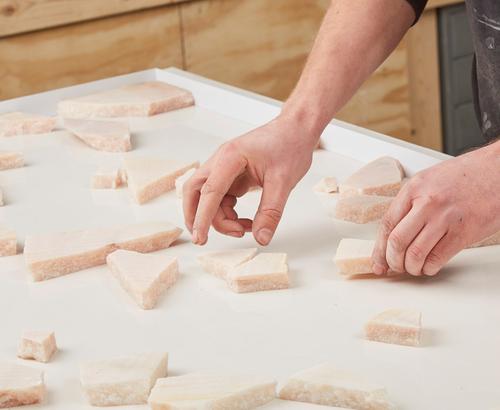 Marble scraps being arranged into a terrazzo pattern