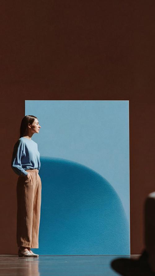 Image of woman in blue sweater standing in front of a blue art piece.