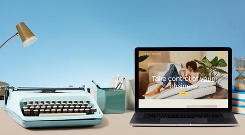 A typewriter next to a laptop displaying a Squarespace landing page.