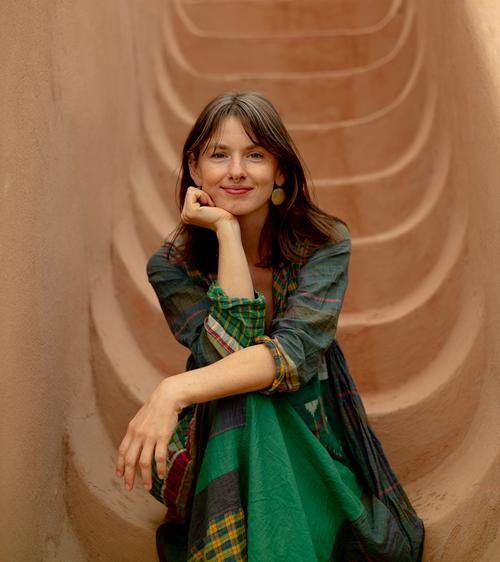 Caitlin Garcia-Ahern, founder of Thread Caravan, smiling against a textured terracotta backdrop.