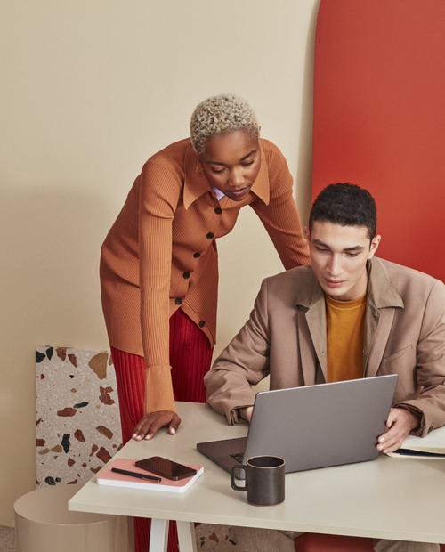 Zwei Personen diskutieren an einem Computer darüber, wie sie ihre Website barrierefreier gestalten können.