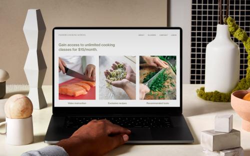 Computadora portátil sobre un mostrador rodeada de objetos decorativos, en la que se ve un sitio web de Squarespace protegido