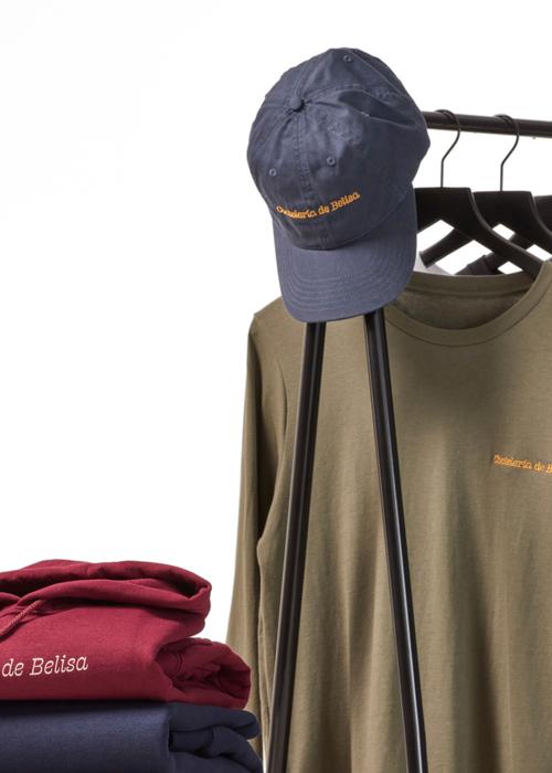 Des t-shirts et une casquette sur un portant