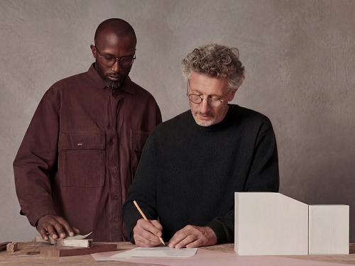 건축 모형이 있는 사무실에서 설계도를 검토하고 메모를 작성하고 있는 나이 많은 건축가와 젊은 건축가