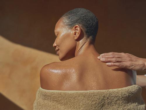 따뜻한 햇살을 받으며 마사지를 받는 사람의 어깨를 클로즈업한 장면