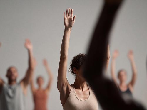 피트니스 수업 중 천장을 향해 손을 들고 있는 사람들 사이에 전면에 선명하게 보이는 여성