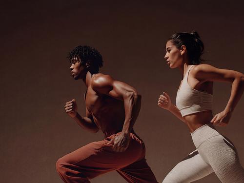 역동적인 조명 아래 나란히 달리는 남녀 운동선수 두 명의 옆모습